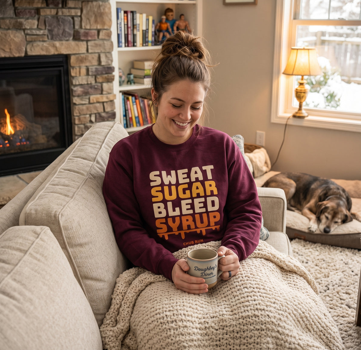 Woman relaxing by a fireplace in the maroon Chub Run Sweat Sugar Bleed Syrup crewneck sweatshirt